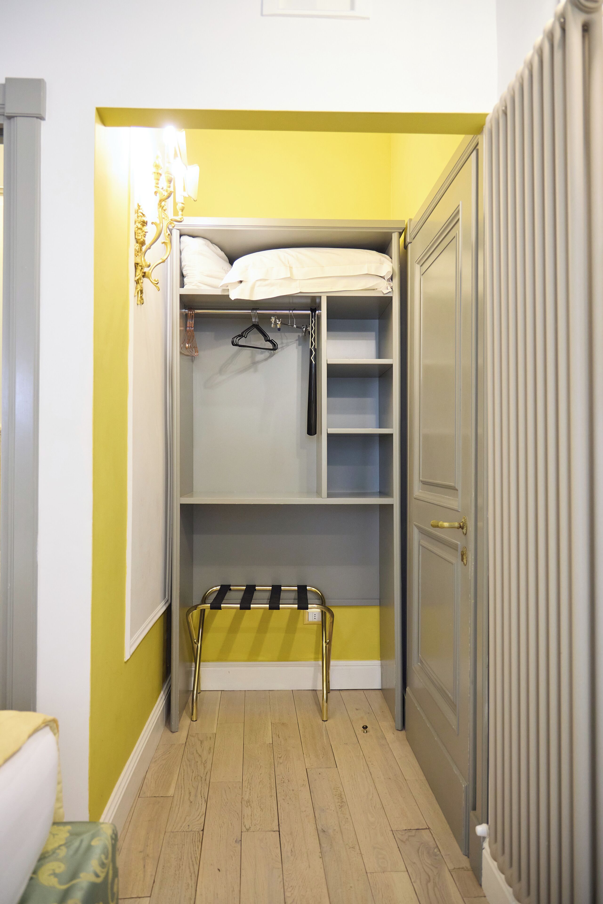 Une petite pièce comprenant un lit superposé, un petit banc et une armoire.