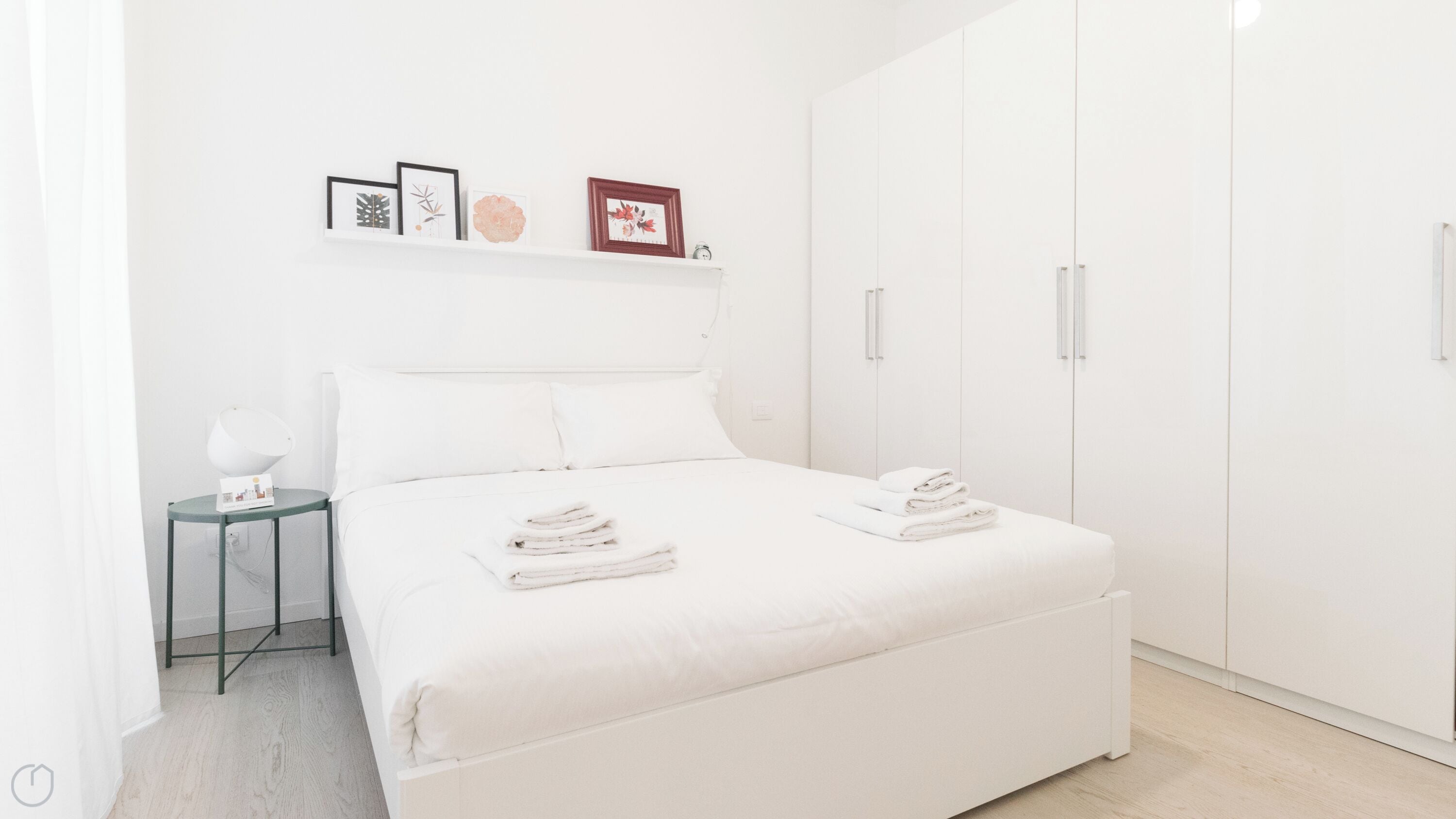 A minimalist bedroom with a large bed, a small bedside table, and a wardrobe.