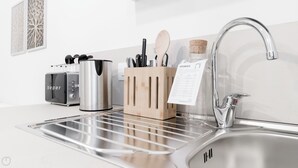 Une cuisine moderne équipée d’un évier en acier inoxydable, d’une machine à café, d’un grille-pain et d’un bloc à couteaux.