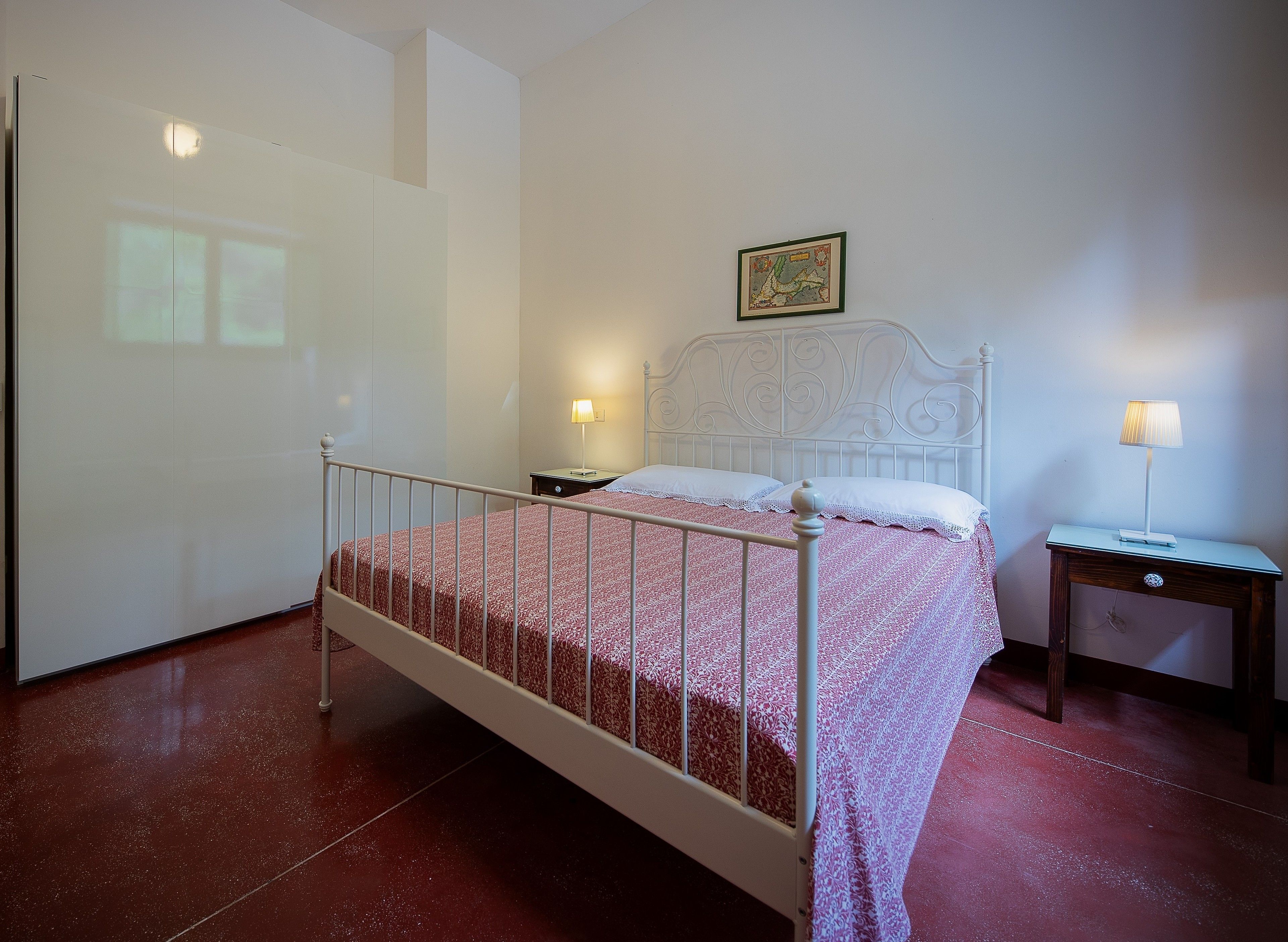 Une chambre à coucher avec un lit, des tables de chevet et une lampe fixée au mur.