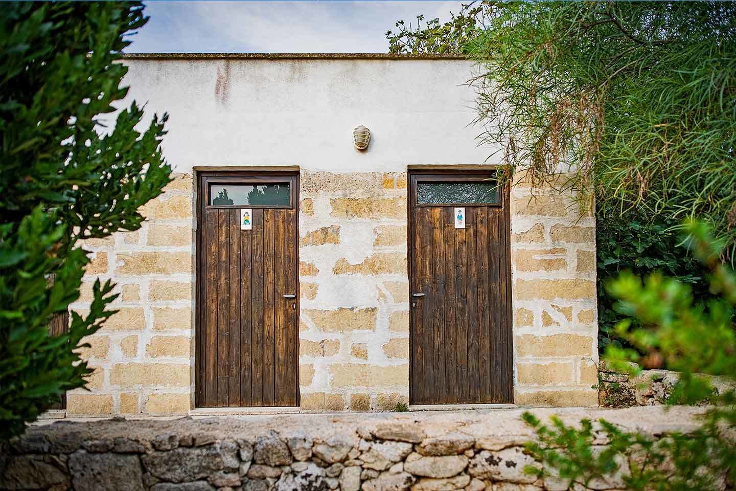 Ein Steinhaus mit zwei Holztüren, jede mit einem kleinen Fenster und einem Schild darüber.