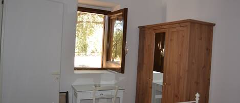 A room with a desk, a chair, a wardrobe, and a window.