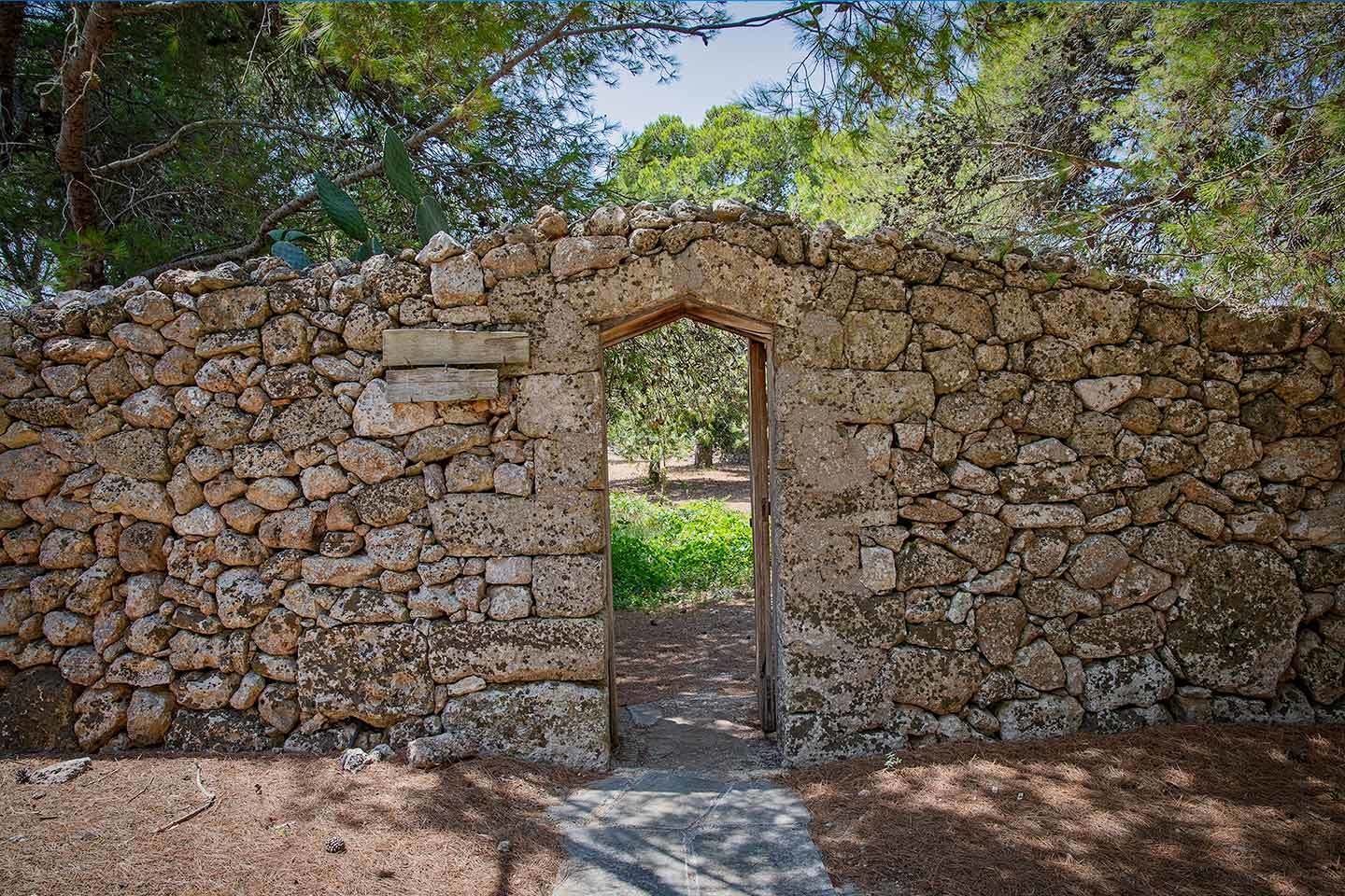 A stone archway leading into a wooded area.