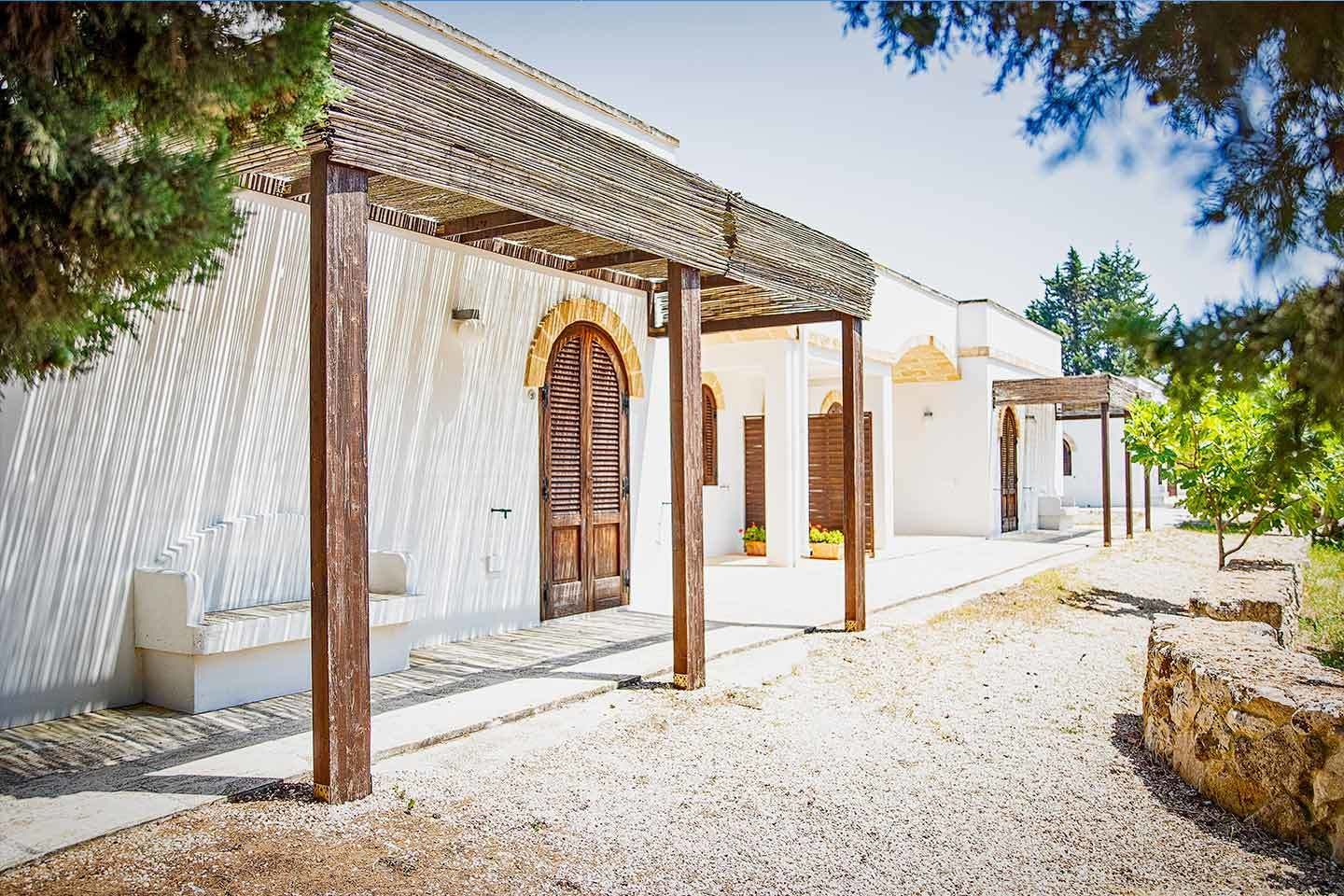 A building with a white exterior, wooden doors, and a covered walkway.