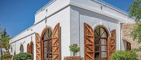 Un edificio con fachada blanca, puertas de madera grandes y ventanas arqueadas.