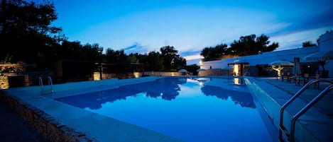 A swimming pool with a stone wall and a stone staircase leading down to the water.