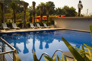 Una piscina al aire libre, sombrillas, sillones reclinables de piscina