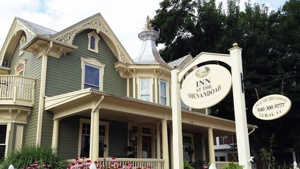 Un bâtiment de style victorien, doté d’un porche, d’une enseigne indiquant « Auberge de Shenandoah » et d’une clôture blanche en piquets.