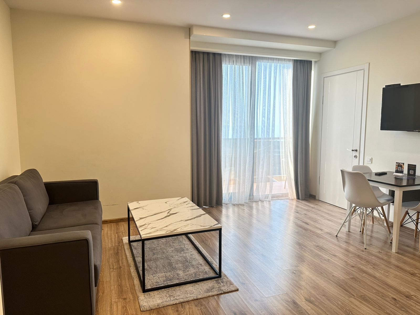 A modern living room with a sofa, a marble coffee table, and a dining area with a table and chairs.