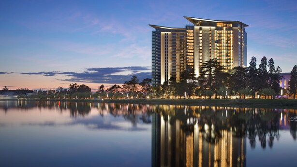 A high-rise hotel with a modern design, situated by a calm lake with reflections of the building and surrounding trees. - Bellevue Residence Suites (Batumi)