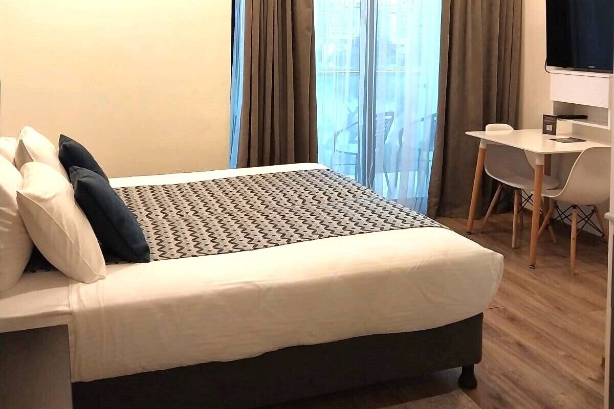 A hotel room with a bed, a desk, and a TV.