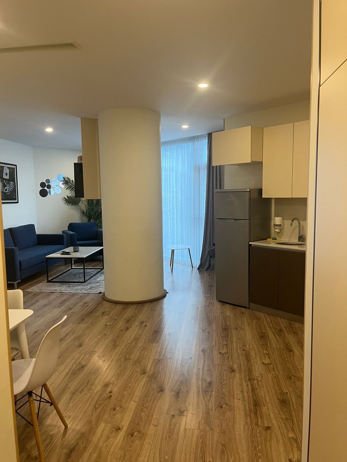 Un appartement moderne comprenant un salon, une cuisine et une grande colonne centrale.