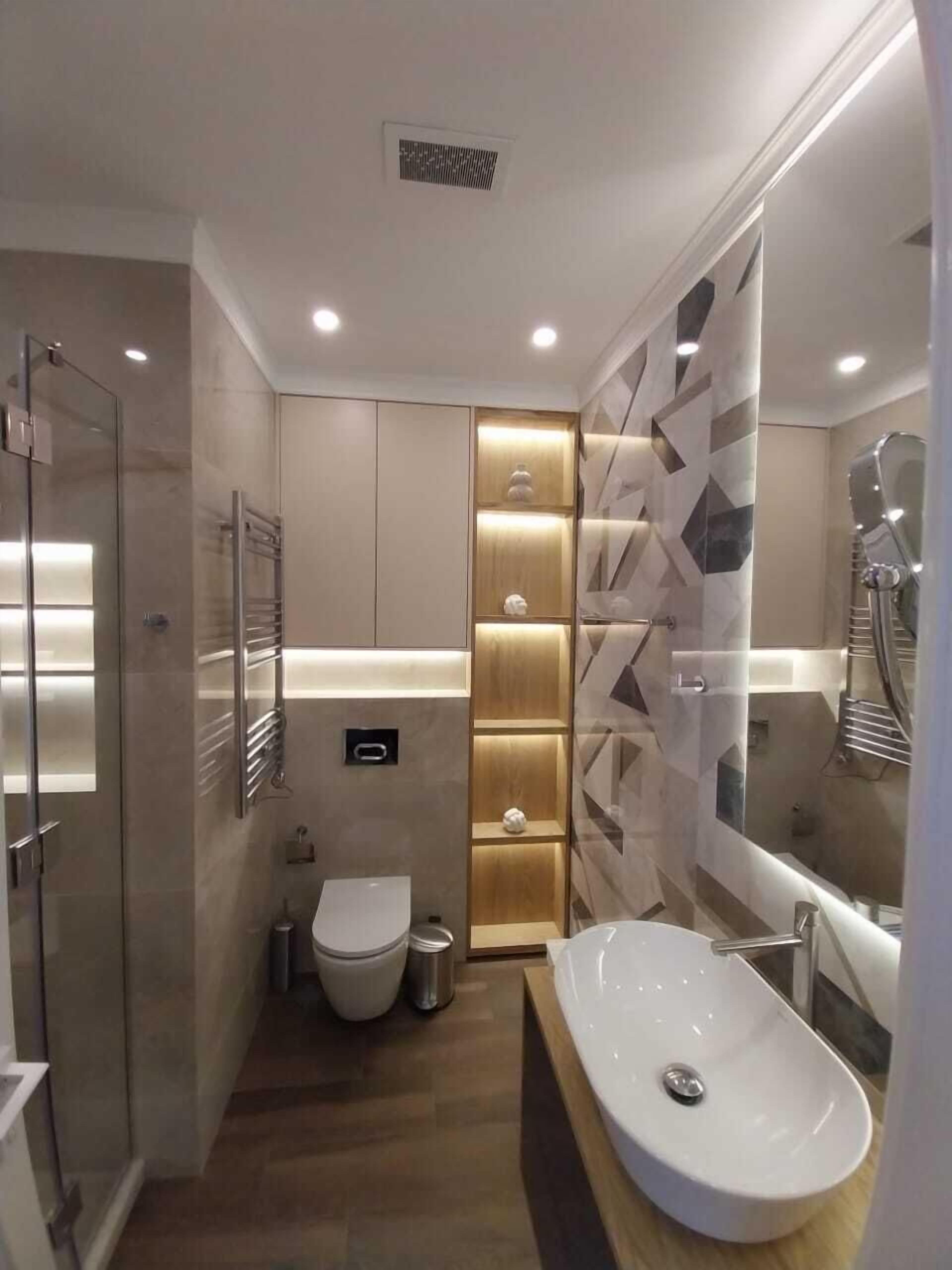 A modern bathroom with a glass shower enclosure, a freestanding bathtub, and a toilet.