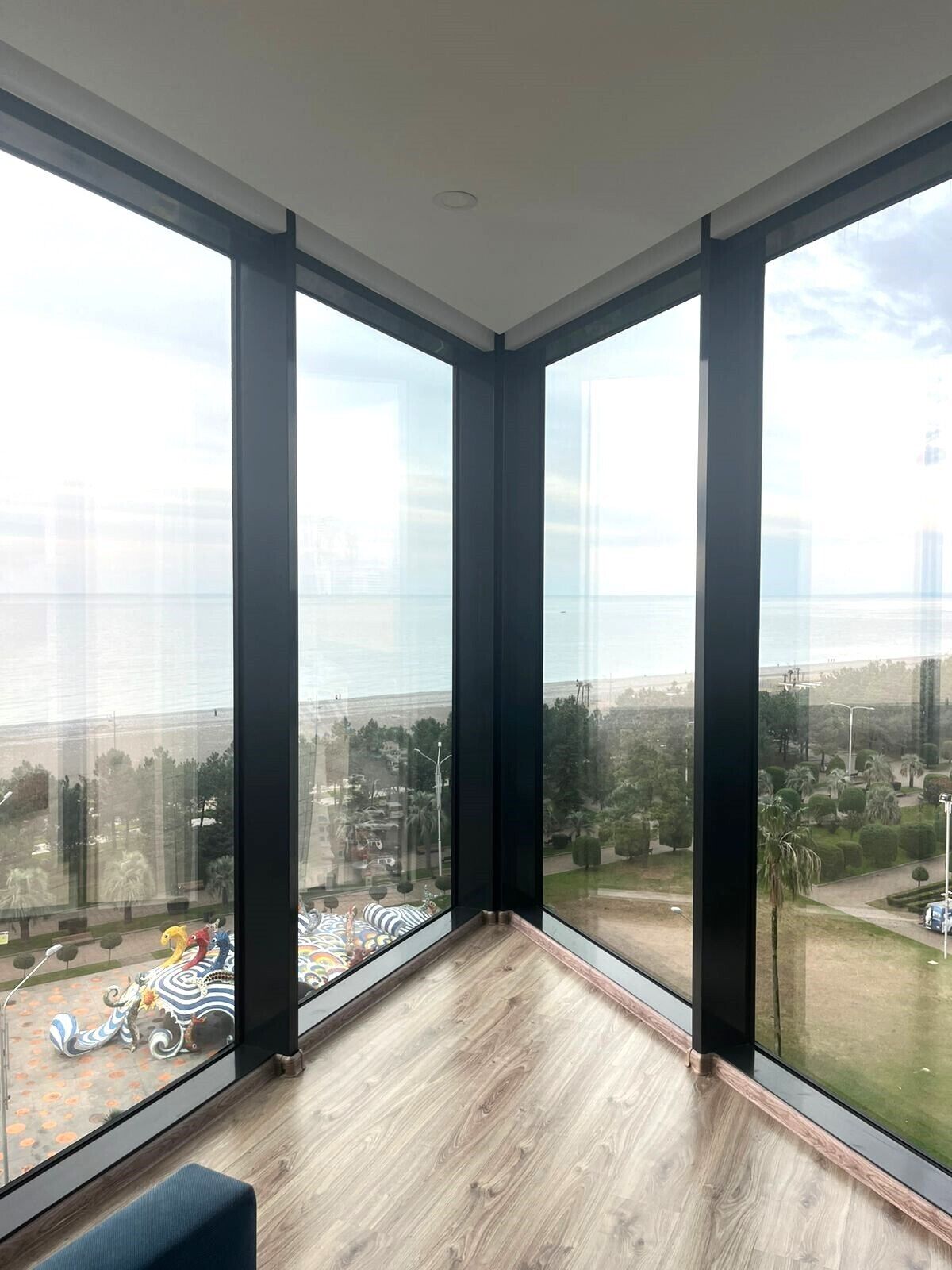 A corner room with large windows, a wooden floor, and a view of a cityscape.