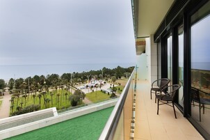 Un balcón con vista a un jardín ajardinado y al mar.