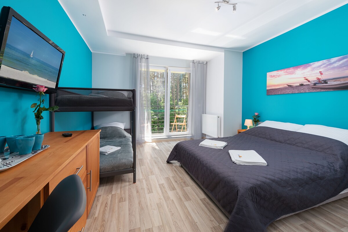 Ein Schlafzimmer mit Bett, Schreibtisch, Stuhl und Fernseher an der Wand.