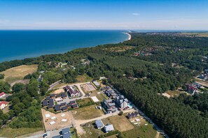 Luftaufnahme einer Küstenwohngegend mit Häusern, einem Strand und dichtem Wald.