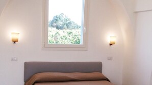 A bedroom with a single bed, a window with a view of greenery, and two wall-mounted lights. - Casale alle Vigne (Nardò)