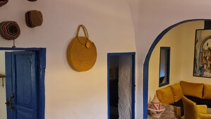 Um quarto com porta azul, cesta de palha, sofá amarelo e um quadro na parede.