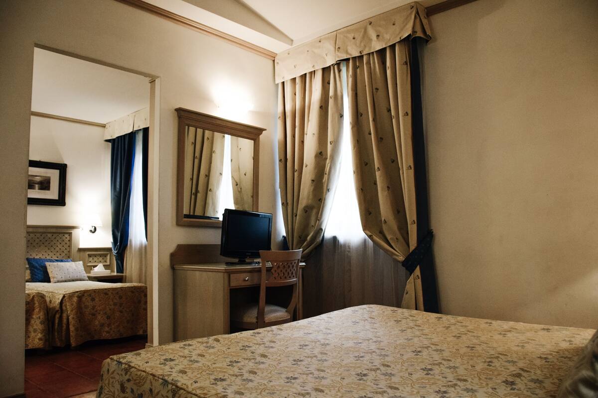 Une chambre d’hôtel comprenant un lit, un bureau avec un ordinateur, une chaise et une armoire.