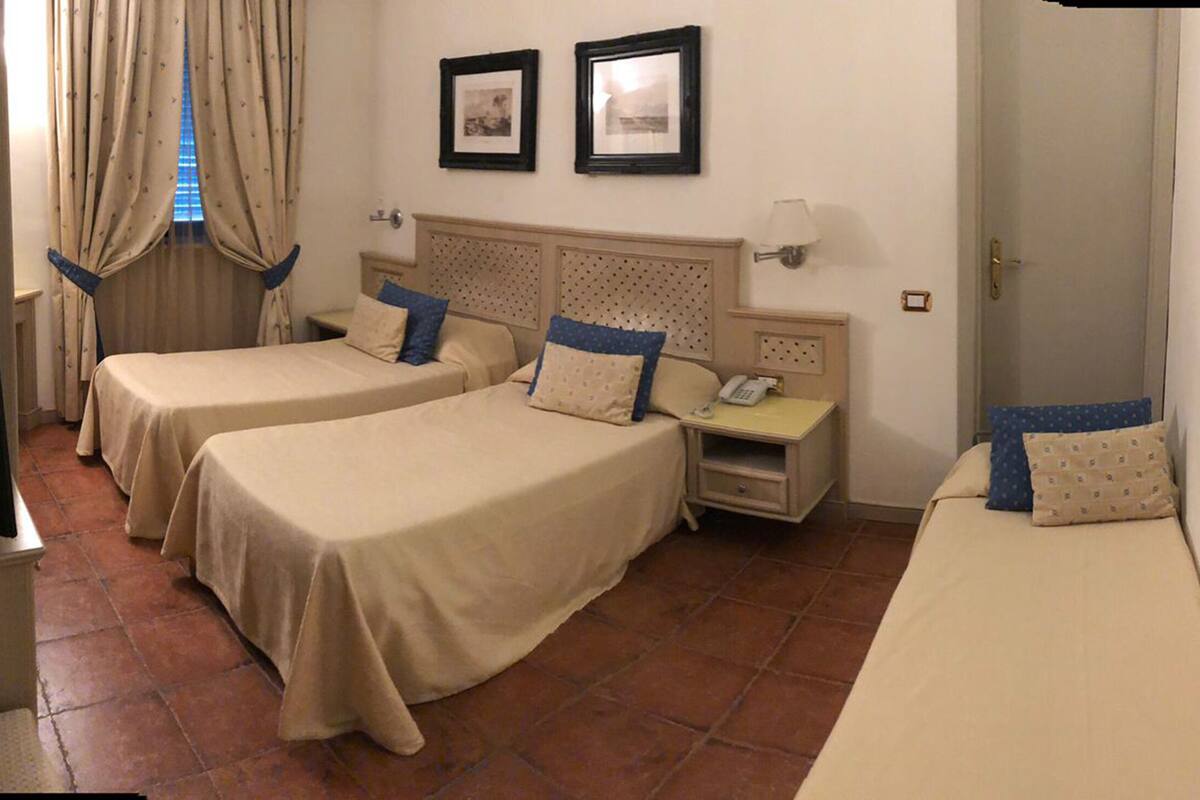 Une chambre d’hôtel avec deux lits simples, une table de chevet avec une lampe, une télévision et un téléphone.