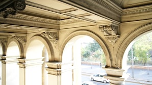 An architectural interior with ornate columns and arches, a clear view of the street outside. - Lucky Holiday Rooms (Rome)