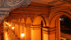 An interior corridor with ornate columns and a series of arches, illuminated by hanging lights. - Lucky Holiday Rooms (Rome)