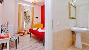 A room with a bed, a chair, a table with a kettle, and a window with curtains. - Lucky Holiday Rooms (Rome)