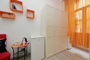 A room with a wardrobe, a table with a kettle, and a red chair. - Lucky Holiday Rooms (Rome)