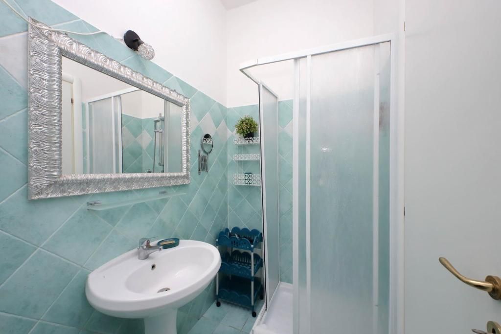 A bathroom with a white sink, a mirror with a silver frame, and a shower area with a glass door.
