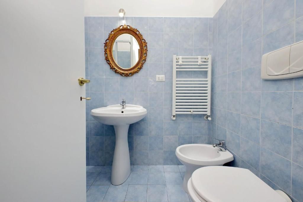 Ein Badezimmer mit einem Standwaschbecken, einem an der Wand befestigten Spiegel, einem Bidet und einem Handtuchhalter.