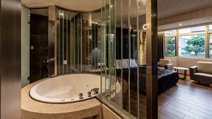 A modern bathroom with a freestanding bathtub, a glass shower enclosure, and a view of a bedroom with a bed and seating area. - King & Princess Motel-Rende (Tainan)
