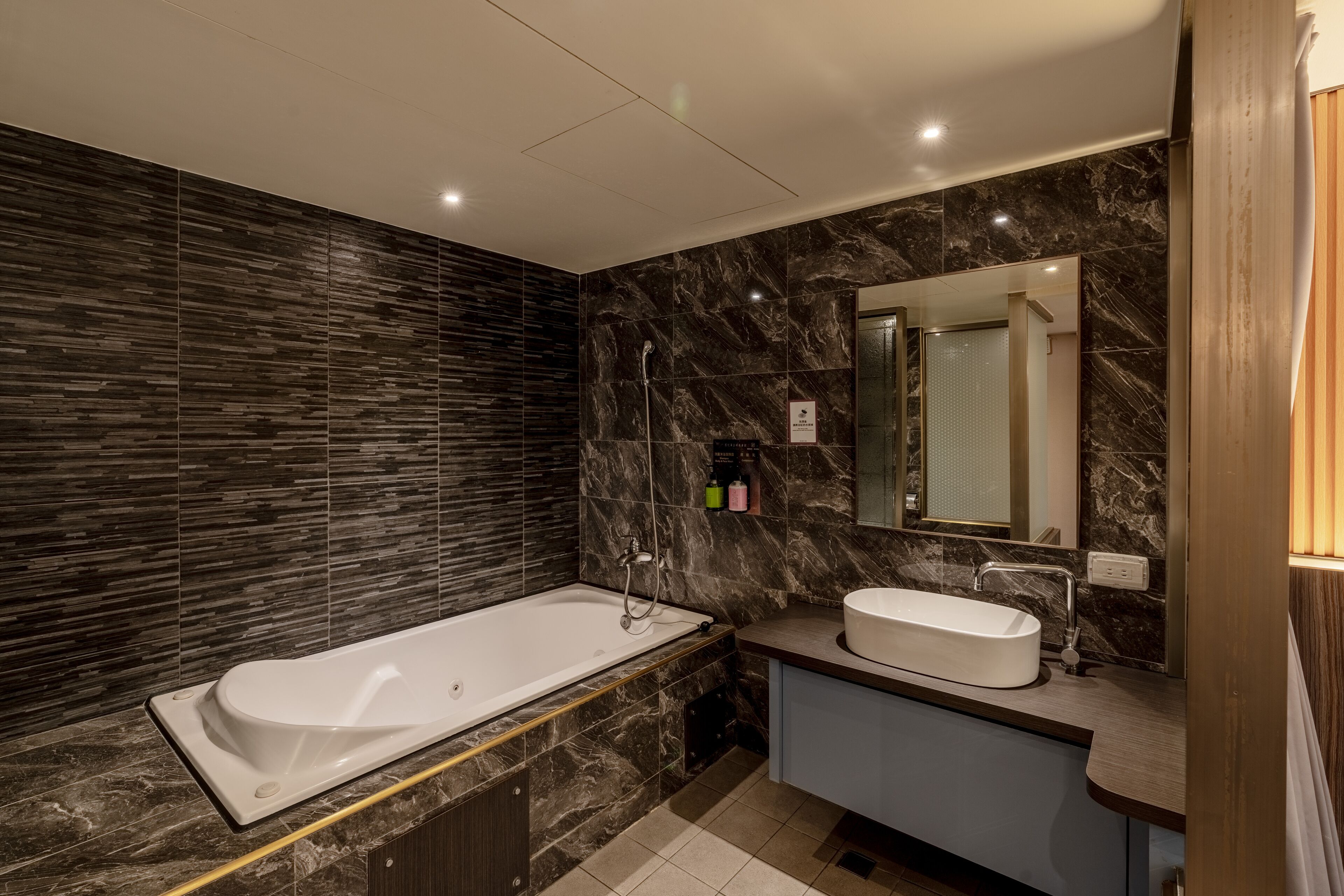 Un baño moderno con una bañera independiente, un tocador con lavamanos y un espejo grande.
