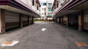 A parking area with a directional arrow on the ground, surrounded by buildings with closed garage doors. - King & Princess Motel-Rende (Tainan)