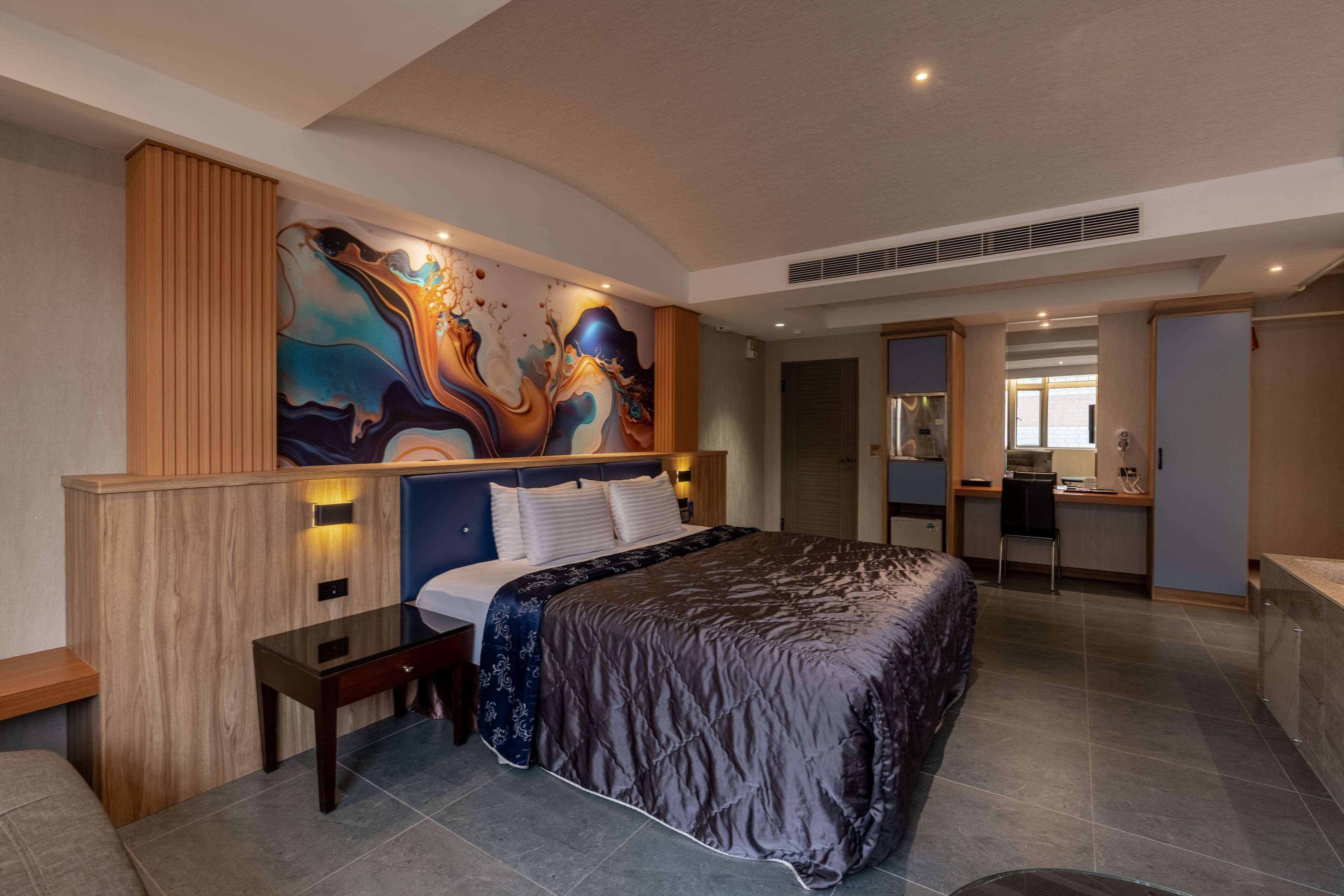 A modern hotel room with a large bed, a desk, and a bathroom.