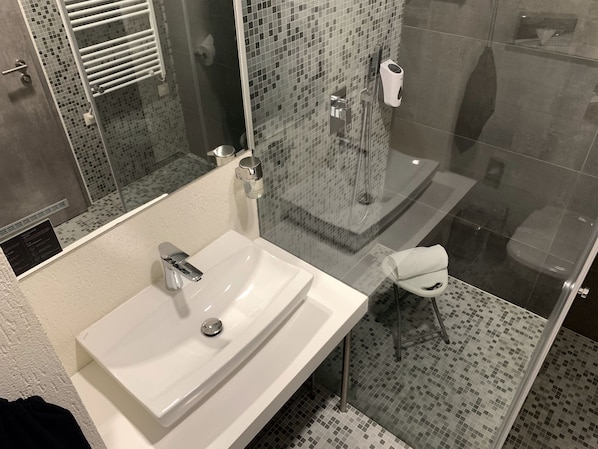 A bathroom with a white sink, a glass shower enclosure, and a tiled floor. - Smart Hotel Budapest (Budapest)