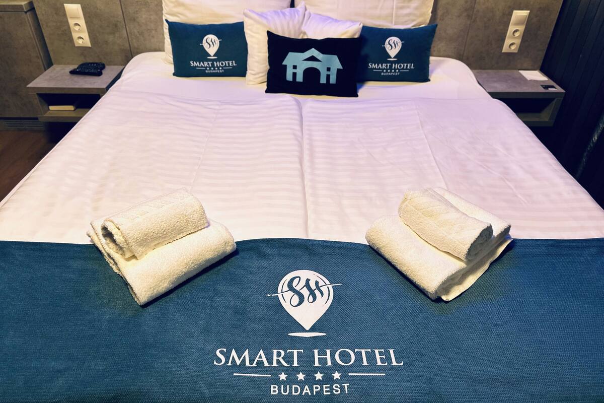 A hotel bed with pillows, a blanket, and towels.