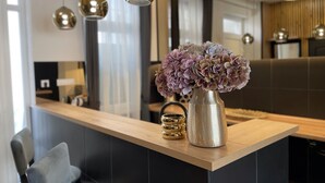 A modern kitchen with a wooden countertop, a vase with flowers, and pendant lights. -  Smart Hotel Budapest (Budapest)