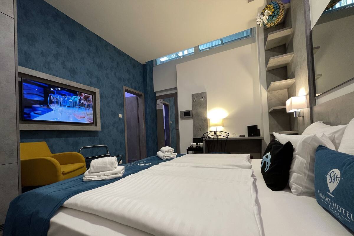 A hotel room with a bed, a TV, a desk, a chair, and a bathroom door.