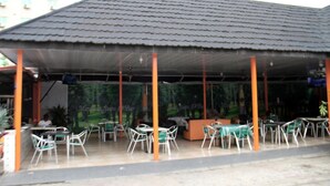 A covered outdoor seating area with tables and chairs, a tiled roof, and a mural on the wall. - Maximus Suites (Lagos)
