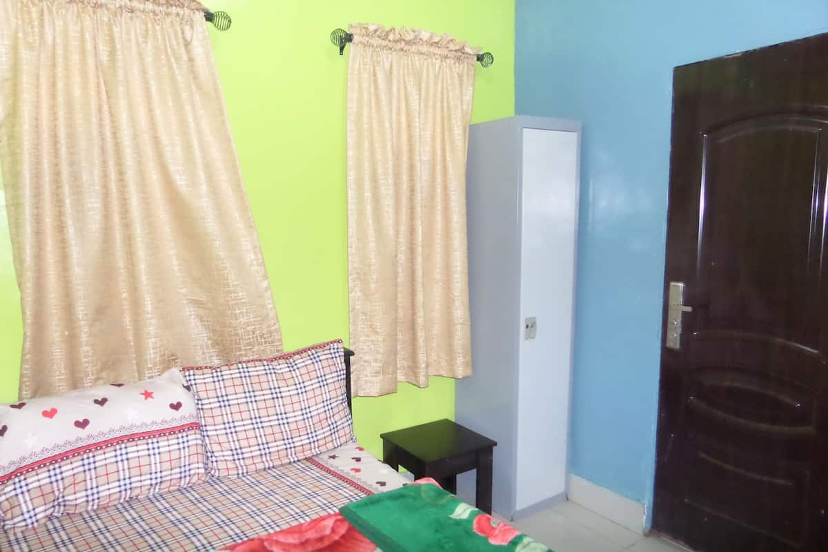 A room with a bed, a small table, a wardrobe, and a door.