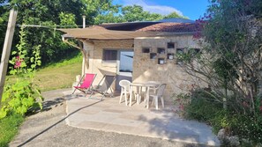 A stone building with a patio, a table, and two chairs.