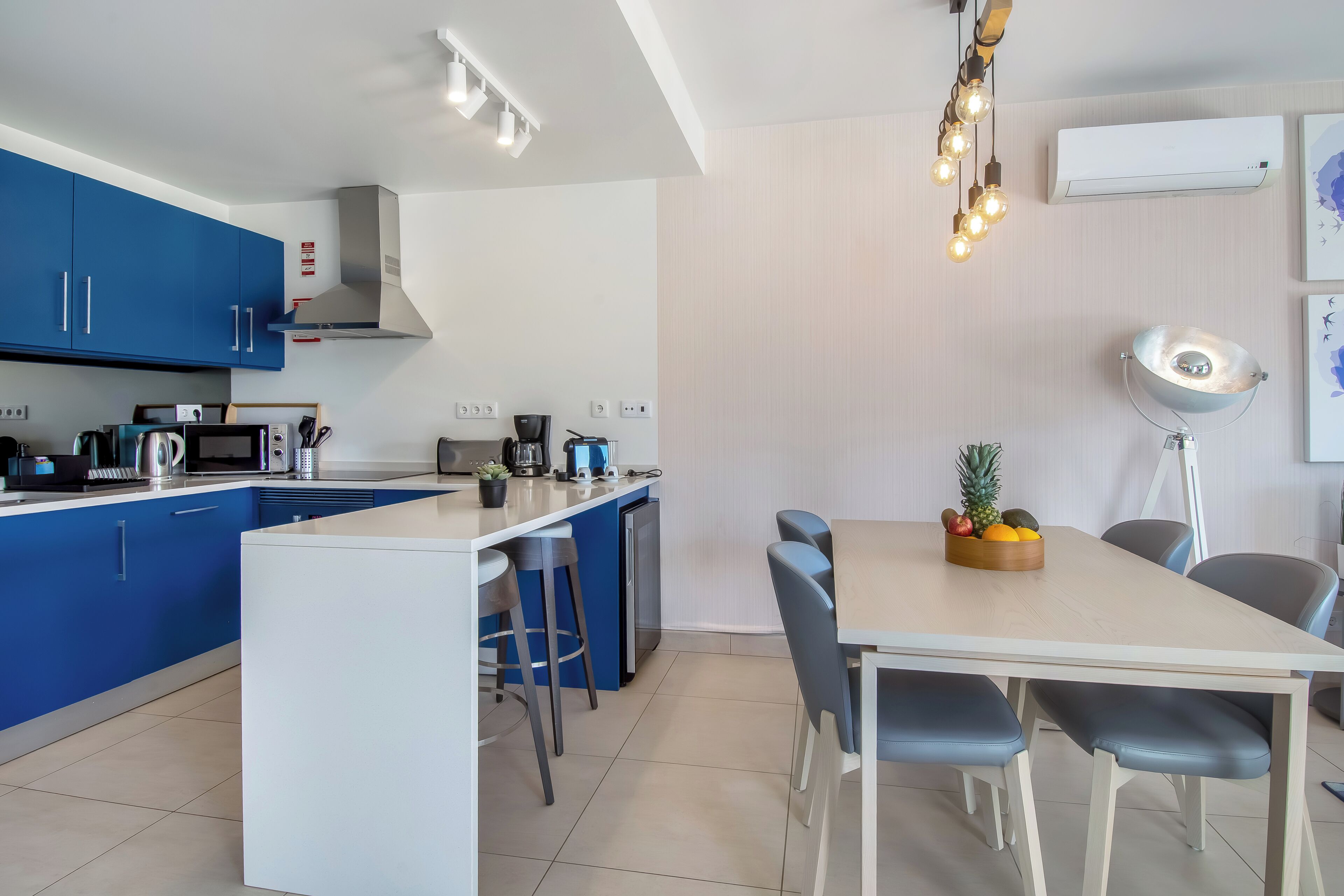 Una cocina moderna con armarios azules, una isla central y una zona de comedor con una mesa y sillas.