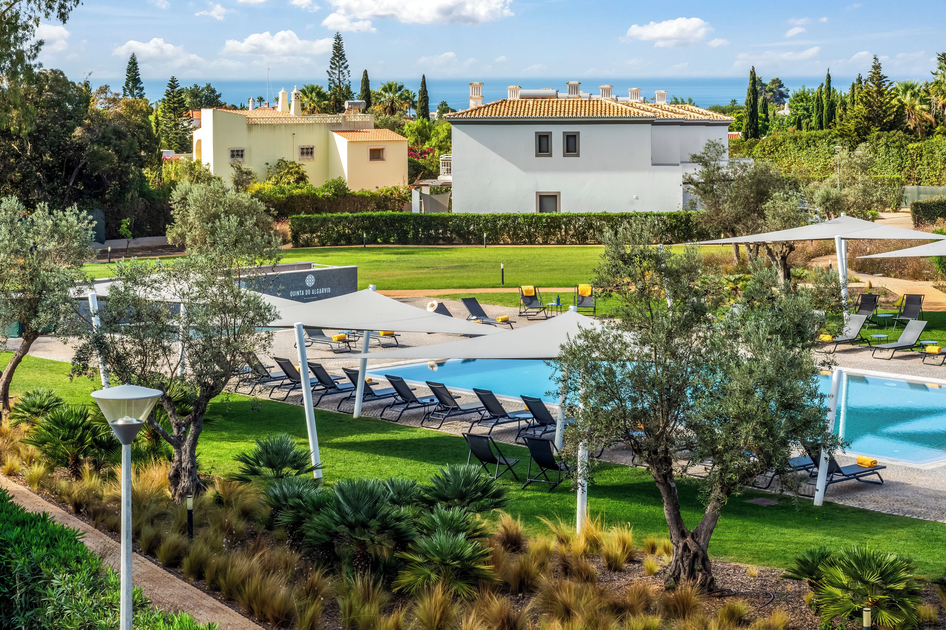 Zona de piscina con sillas de descanso, un espacio de estar techado y vistas al mar.