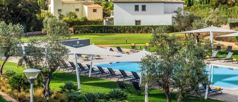 Zona de piscina con sillas de descanso, un espacio de estar techado y vistas al mar.