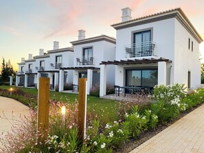 A row of modern, white houses with balconies, a paved walkway, and flowering plants. - Quinta do Algarvio (Lagoa)