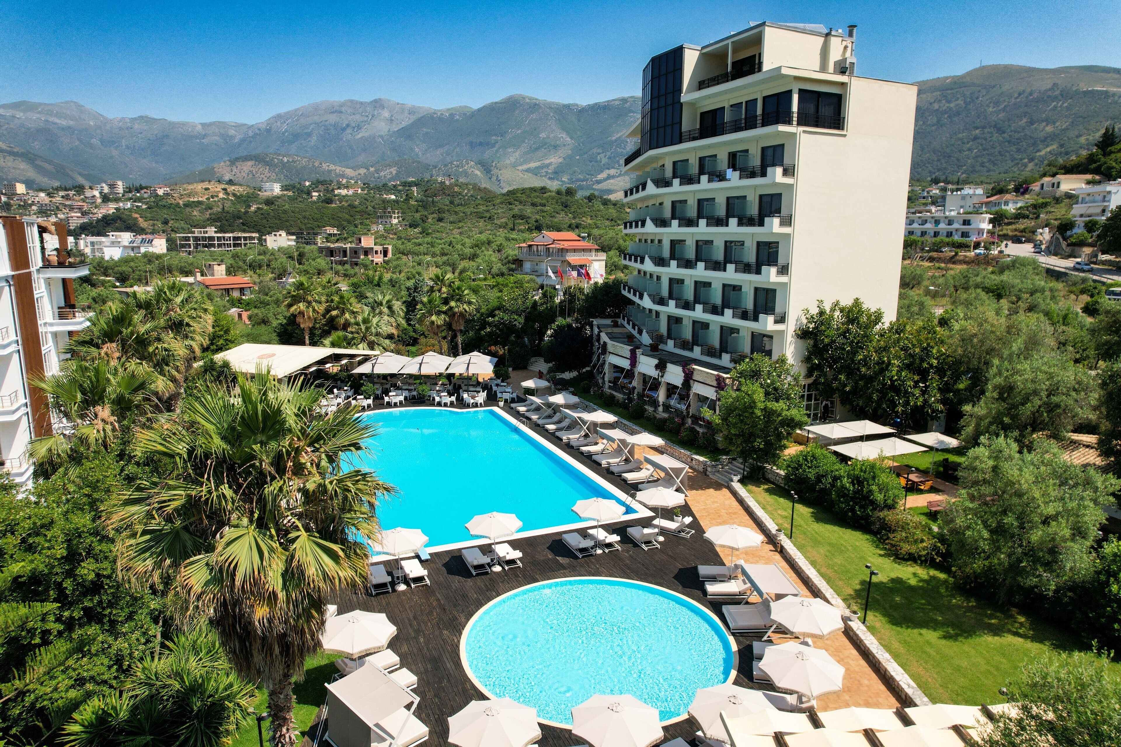 Um hotel com piscina, cadeiras de descanso e vista para montanhas.