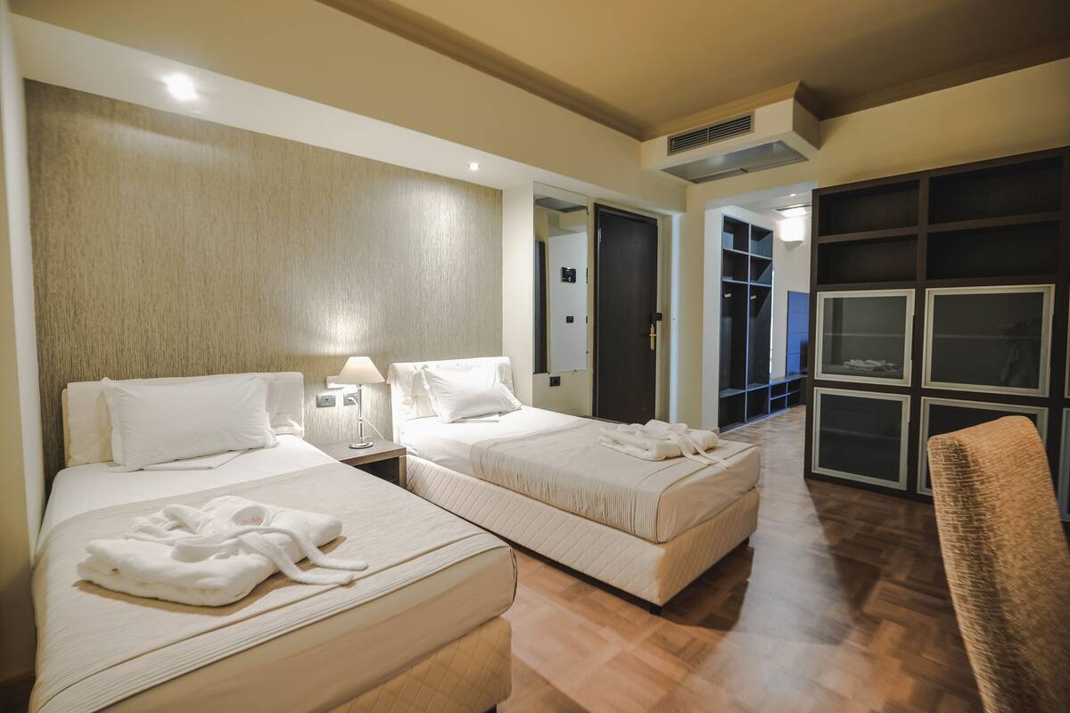 A hotel room with two beds, a sitting area, and a wardrobe.