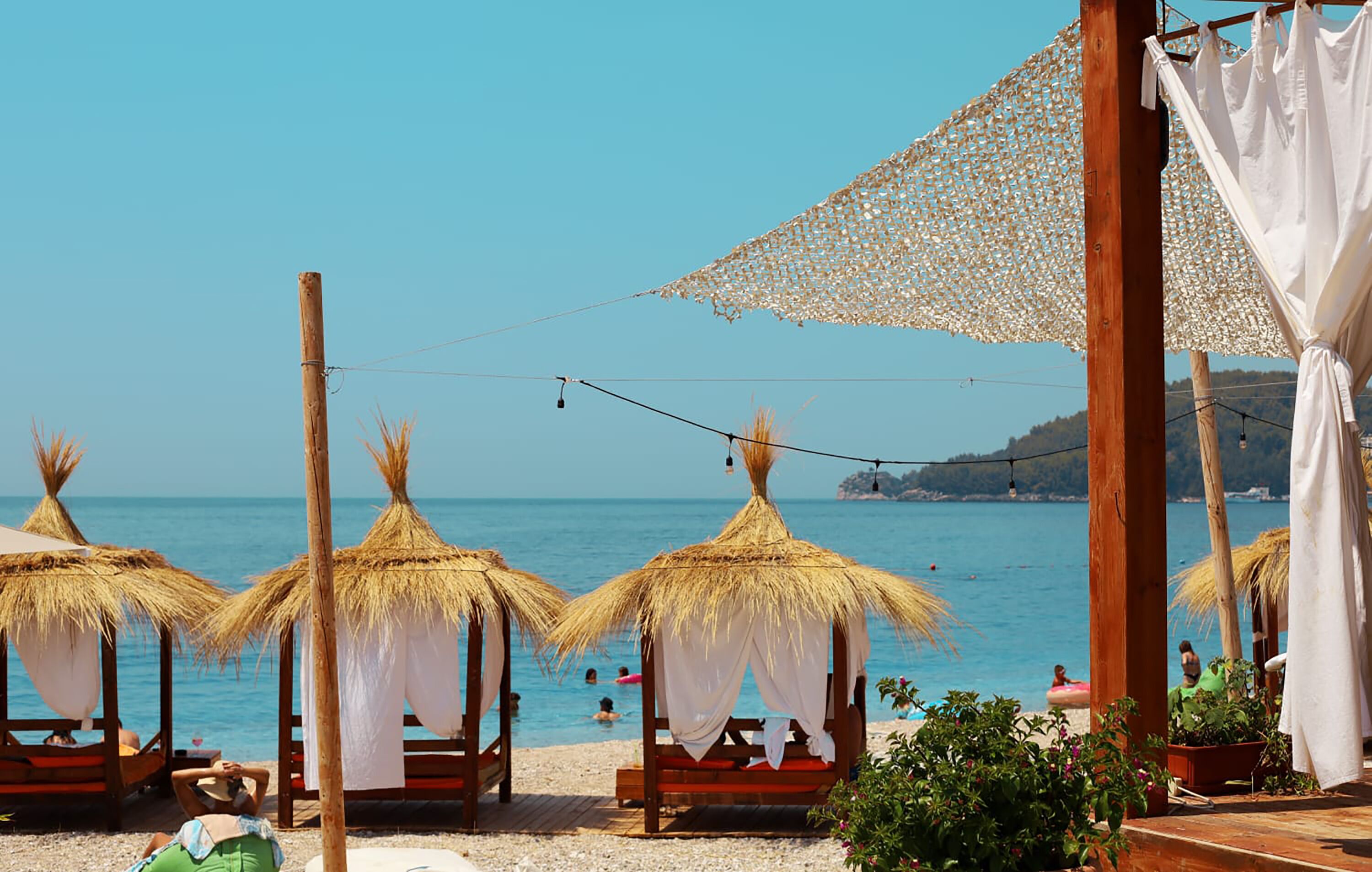 A beach with thatched umbrellas and wooden benches.