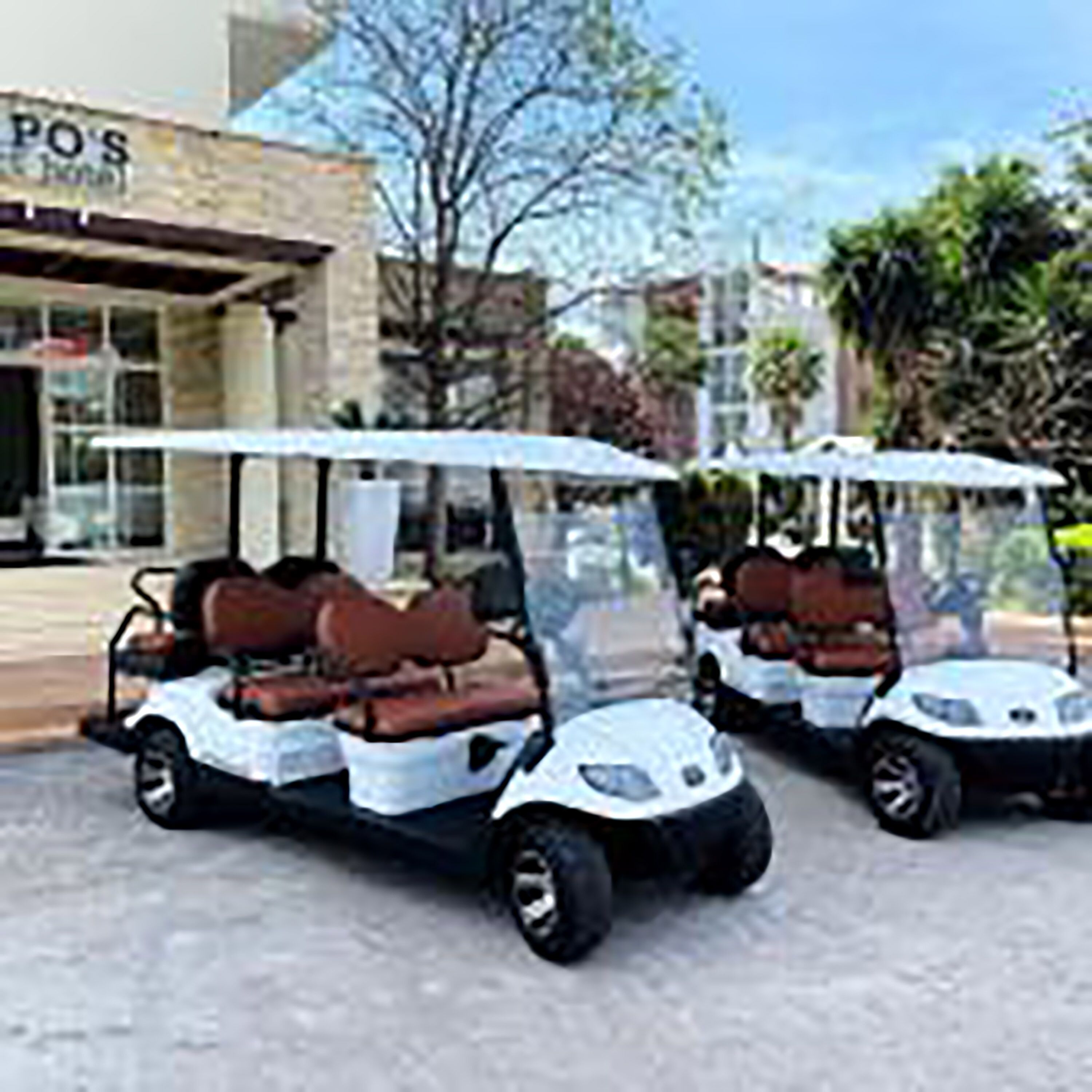 Two golf carts parked in front of a building with a sign that reads "POS".